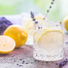 Orzeźwiająca lemoniada lawendowa z cytrynami i lodem, ozdobiona gałązką lawendy.