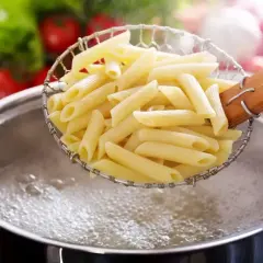 Penne prosto z gotowania, idealnie makaron al dente, unoszone nad bulgoczącą wodą.