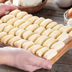 Ania gotuje pierogi leniwe. Na desce leżą rzędy gotowych do gotowania pierogów z twarogu.