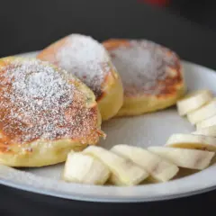 Szybkie placuszki na śniadanie, posypane cukrem pudrem, z kawałkami banana. Idealne na poranny posiłek.