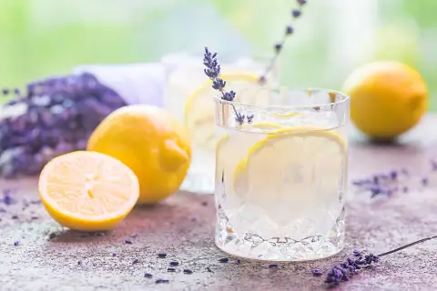 Orzeźwiająca lemoniada lawendowa z cytrynami i lodem, ozdobiona gałązką lawendy.
