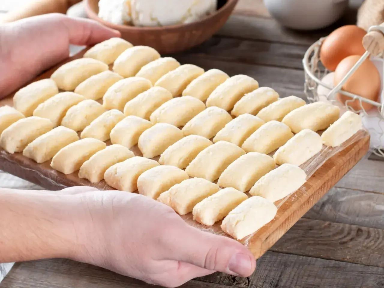Ania gotuje pierogi leniwe. Na desce leżą rzędy gotowych do gotowania pierogów z twarogu.