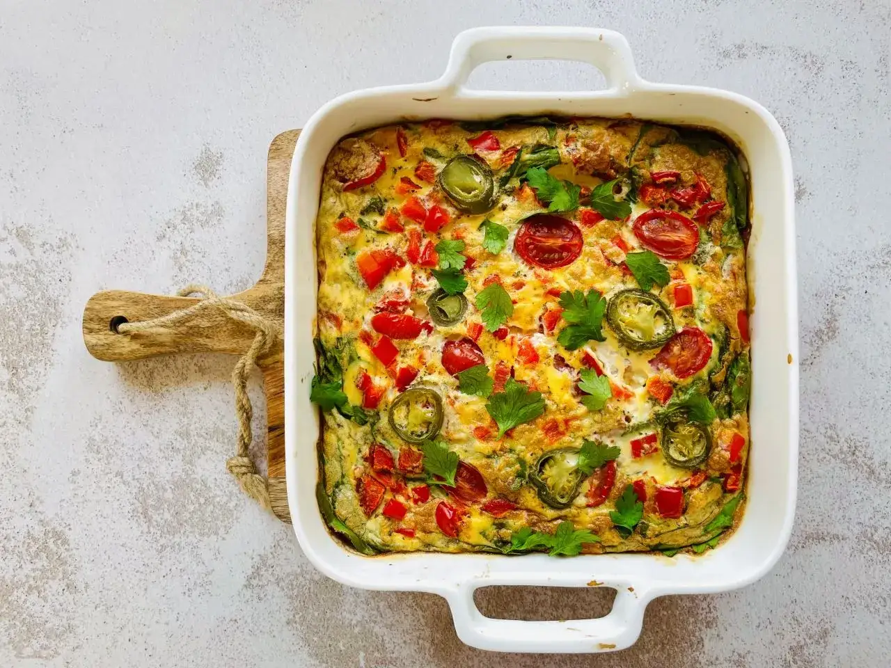Kolorowy omlet z piekarnika z pomidorkami, papryką i jalapeño, udekorowany natką pietruszki. Pyszne danie na śniadanie lub brunch.